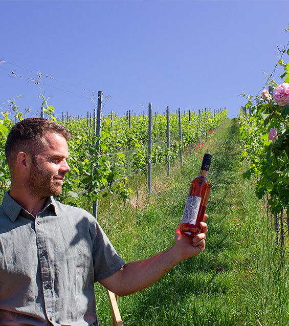 Andreas Dobler mit Weinflasche im Weinberg mit Leidenschaft zum Handwerk
